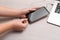 Woman connecting smartphone with charge cable to laptop on light grey table, closeup. Space for text