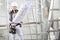 Woman construction worker builder looking at bluprint, wearing helmet, hearing protection headphones and tools belt bag in