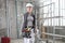 Woman construction worker builder wearing white helmet and tools belt bag,  on interior site building background with