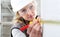 Woman construction worker work with meter tape and pencil, measure wall in interior building site, wearing helmet, glasses and