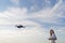 A woman controls the flight of a drone. The quadcopter hovered in the air, the female drone pilot looks at the drone