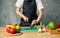 Woman cook black apron slicing vegetables cutting board kitchen cooking food