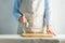 Woman cook in a cotton apron holds a cutting board and a knife in her hands. Rustic natural style. Kinfolk concept.