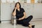 A woman cook sits on the floor and holds a professional mixer next to her