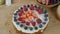 Woman cooking berry cake and decorating biscuit with raspberries