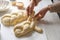 Woman cooking braided bread at white wooden table in kitchen, closeup. Traditional Shabbat challah