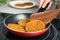 Woman cooking breaded cutlets in frying pan on stove, closeup