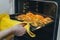 Woman cooking in the kitchen, puts cakes in the oven