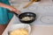 Woman cooking a meal frying onions in a pan