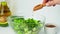 Woman cooking salad of fresh green vegetables and herbs. Cooking healthy diet or vegetarian food. Female hands add flax