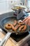 Woman cooking sausages in pan on kitchen cooking plate with fork and black spatula with delicious fatty bratwurst for dinner as un