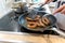 Woman cooking sausages in pan on kitchen cooking plate with fork and black spatula with delicious fatty bratwurst for dinner as un