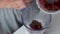 Woman is cooking smoothies putting frozen strawberries in blender cup, closeup.