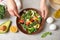 Woman cooking tasty kale salad on light grey table