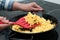 Woman cooking tasty scrambled eggs in wok pan on stove