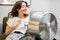 Woman cooling herself with a fan at home