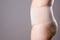 Woman in corrective panties, overweight female body in shapewear on gray background