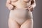 Woman in corrective panties, overweight female body in shapewear on gray background