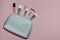 Woman cosmetic bag, make up beauty products on pink background. Makeup brushes and pink lipstick. Top view, flatlay. Decorative co