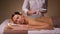 Woman and cosmetologist applying clay mask in spa