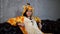 Woman in costume of giraffe sitting on couch. Smiling young woman in funny pyjamas of giraffe sitting on leather couch