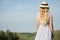 Woman in a cotton dress and a straw hat in a field. Standing in the meadow. back view copycpase