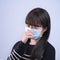 Woman coughing with mask - young Asian covering the mouth, feeling unwell with wearing medical blue face mask isolated on white