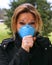 Woman coughs in sickness while wearing a blue antiviral face mask to protect from sickness.