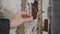 A woman counts out old paint from the window of an abandoned house with her fingers.