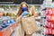 Woman courier volunteer in a medical mask holds a paper bag with products. Shopping during the covid-19 pandemic