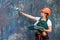 Woman in coverall and helmet painting wall with roller