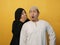 Woman covering her mouth and whispering secret to her husband ear, Asian muslim man looking shocked and excited, opening eyes and