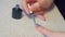 Woman is covering nails applying grey shellac gel polish at home, hands closeup.