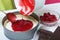 A woman covers coconut flakes in a sponge cake with chocolate ganache with raspberry jelly. Levington cake, stages of preparation