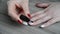 Woman covers her fingernails with her colorless varnish over a colored