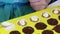 A woman covers melted chocolate filling with crushed almond, which is in silicone form. Cooking candies glazed in white and black