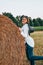 Woman in cowboy hat staying near a straw bale. Summer, beauty, fashion, glamour, lifestyle concept. Cottagecore farmcore