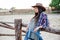 Woman cowgirl in hat and plaid shirt standing outdoors