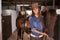 Woman or cowgirl, portrait and horse in barn to train or feed and grooming for animal or pet care. Person, stallion and