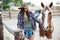 Woman cowgirl walking with her horse on ranch