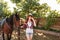 Woman cowgirl walking with her horse in village