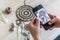 Woman craftsman photographing dreamcatcher use smartphone at workshop for internet advertising