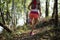 Woman cross country trail running in forest