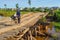 Woman crosses unsafe wooden bridge, Indonesia