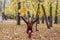 The woman crouched in the park in the fall and throws up yellow leaves.