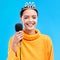 Woman, crown and microphone in studio portrait with smile for singing, recording or performance by blue background