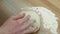 Woman crumples the dough on wooden surface