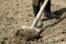 A woman cultivates land on a farm, part of the boots and the shovel can be seen