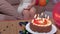 Woman with cup of coffee sitting on sofa near birthday party cake with burning candles