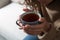 Woman with cup of hot tea indoors, closeup. Cozy home atmosphere